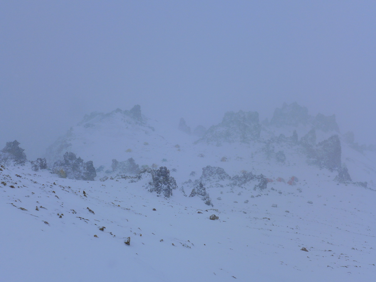 В снежном тумане внизу впереди палатки лагеря Колера